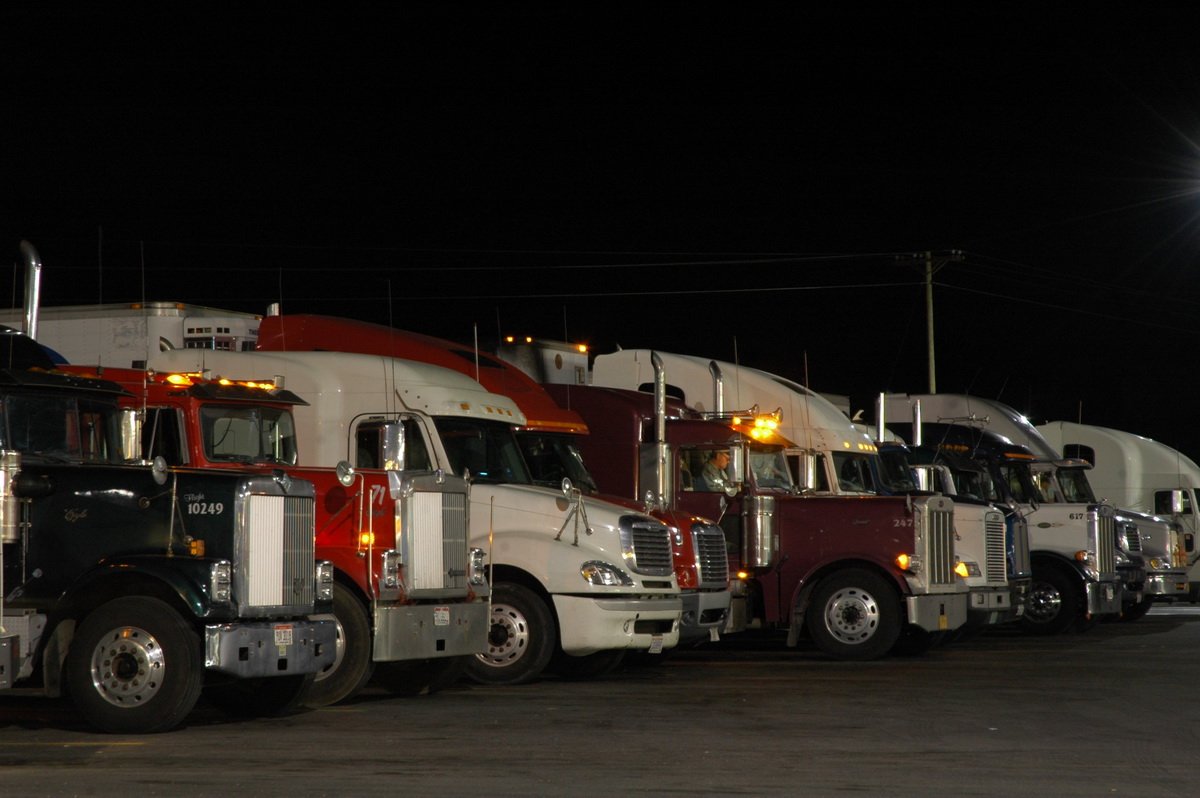 Semi tractors parked under night yard lights beside Georgia's free DDS CDL study guide download
